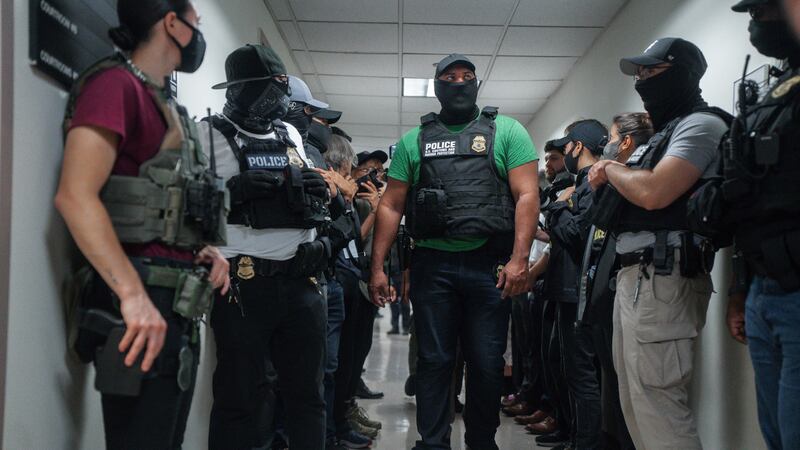 ARCHIVO - Agentes federales enmascarados esperan afuera de una sala de audiencias de...